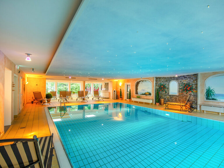 Ein elegantes Hallenbad im Braunschweiger Hof, umrahmt von bequemen Liegen.