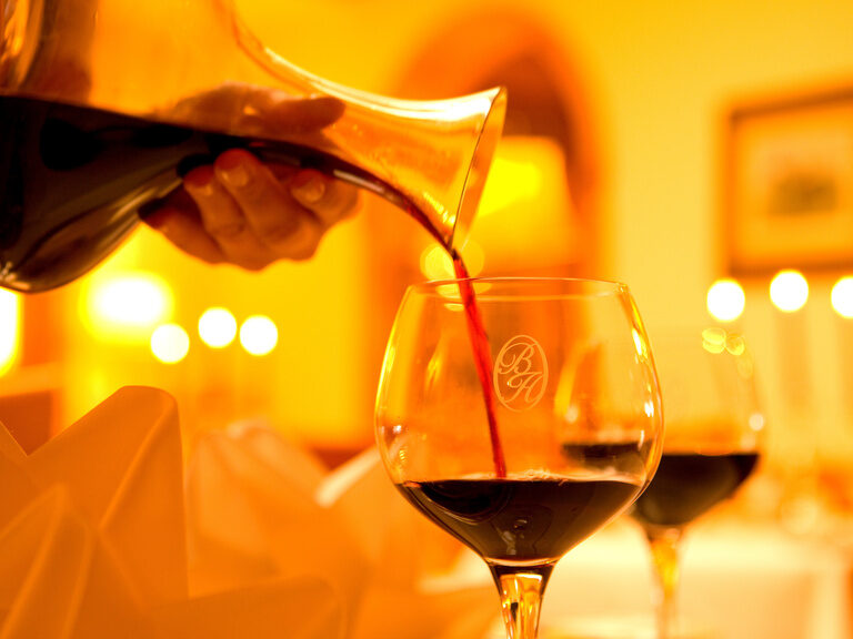 Eine Person schenkt Rotwein in ein luxuriöses Glas ein im Restaurant des Braunschweiger Hof.